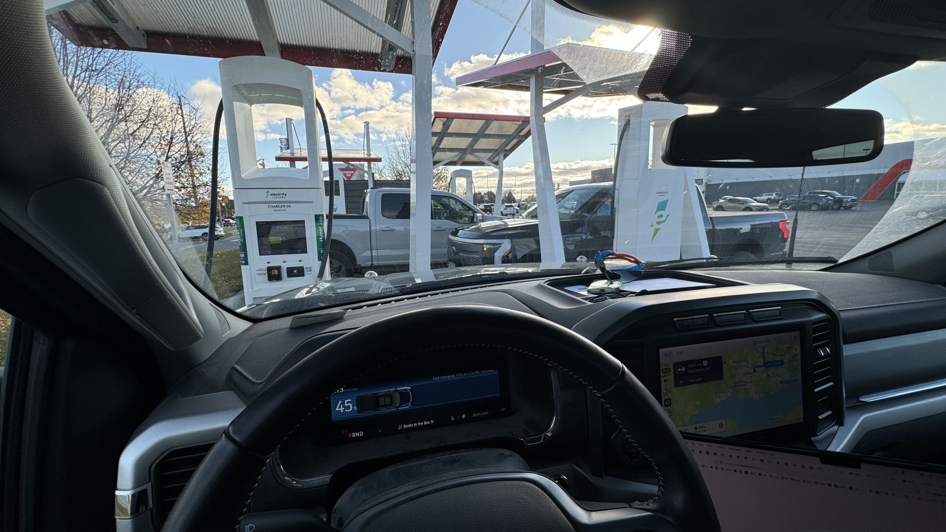 Photo out the front window of my Ford F150 Lightning EV, charging - with two more Lightnings charging beyond.